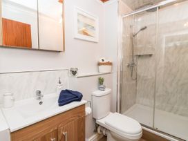 A bathroom with a sink cabinet a toilet with a plant on the tank and a shower enclosure at Millers Cottage in Old Malton near Malton
