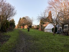 A garden area with a dirt path trees a greenhouse and a grass lawn at Millers Cottage in Old Malton near Malton