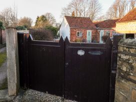 A dark wooden gate with a house and trees in the background at Millers Cottage in Old Malton near Malton
