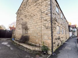 The exterior of a stone building with windows and a small garden area near a paved street at Millers Cottage in Old Malton near Malton