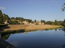A river with trees fields and stone ruins in the background at Millers Cottage in Old Malton near Malton