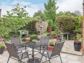 A garden patio with a glass table and four chairs surrounded by plants and greenery at Millers Cottage in Old Malton near Malton