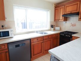 A kitchen with wooden cabinets white countertops a microwave dishwasher sink stove and window at Seaward in Rhos-On-Sea