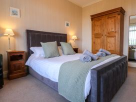 A bedroom with a bed a wooden wardrobe two lamps and a mirror at Seaward in Rhos-On-Sea