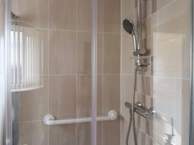 A shower enclosure with a handheld showerhead and a grab bar at Seaward in Rhos-On-Sea