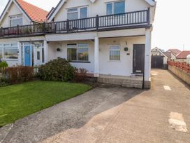 Exterior view of a semi detached house with a balcony driveway and lawn at Seaward in Rhos On Sea