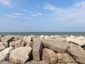 A rocky shoreline with sea and wind turbines in the distance at Seaward in Rhos-On-Sea