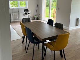 A dining room with a wooden table and colorful chairs at 30 River Run in Belturbet
