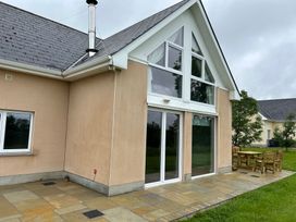 A building exterior with large windows and patio furniture at 30 River Run Belturbet