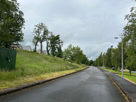 An outdoor scene with a road lined by trees and houses at 30 River Run in Belturbet