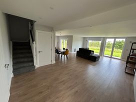 A living room with a staircase, table, chairs, and sofa at 30 River Run, Belturbet, County Cavan