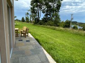 A patio with a table and chair overlooking a lawn and trees at 30 River Run Belturbet, County Cavan
