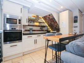 A kitchen with appliances and a dining table at Pine Cottage Dinas Dinlle