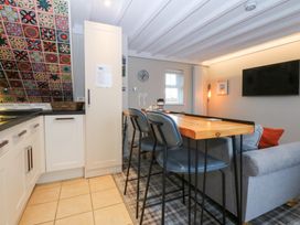 A kitchen with bar stools and a dining table at Pine Cottage in Dinas Dinlle