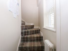 A staircase with plaid carpet at Pine Cottage Dinas Dinlle