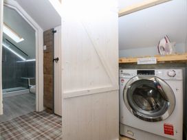 A laundry room with a washing machine and a doorway to a bathroom at Pine Cottage Dinas Dinlle