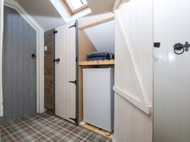 A storage room with a fridge and shelves at Pine Cottage Dinas Dinlle