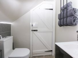 A bathroom with a toilet, sink, towels and a door at Pine Cottage in Dinas Dinlle