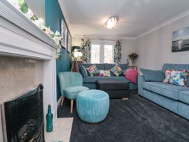 A living room with blue sofas colorful cushions a fireplace and a turquoise chair with matching ottoman at 48 Aysgarth Rise Bridlington