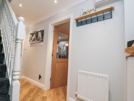 A hallway with stairs carpeted in dark fabric a wooden floor a radiator a wall-mounted coat rack a door leading to another room and a black and white picture on the wall at 48 Aysgarth Rise in Bridlington