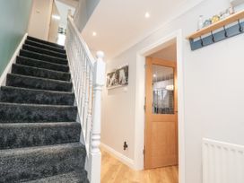 A hallway with carpeted stairs and a wooden door with glass panels at 48 Aysgarth Rise in Bridlington