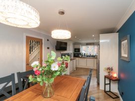 A dining area with a wooden table and chairs and a kitchen with white cabinets at 48 Aysgarth Rise in Bridlington