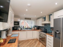 A kitchen with white cabinets wooden countertops stainless steel appliances and blue tiled backsplash at 48 Aysgarth Rise in Bridlington
