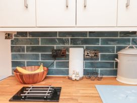 A kitchen countertop with a wooden bowl holding bananas a paper towel roll with ceramic bunny figures two power outlets a wire egg holder a bread container and a blue mat at 48 Aysgarth Rise Bridlington