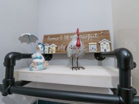 A wooden shelf with a duck figurine holding an umbrella a chicken ornament and a wooden sign with decorative houses at 48 Aysgarth Rise in Bridlington
