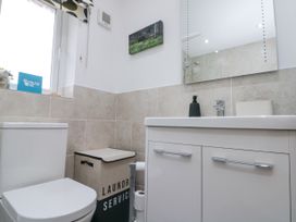 A bathroom with a toilet a laundry basket a sink cabinet and a mirror at 48 Aysgarth Rise in Bridlington
