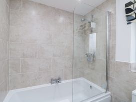 A bathroom with a bathtub shower combination with beige tiled walls at 48 Aysgarth Rise in Bridlington