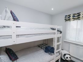 A bedroom with white bunk beds pillows folded blankets a window with blinds and a panda toy near a radiator at 48 Aysgarth Rise in Bridlington