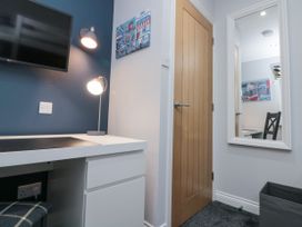 A desk with a lamp and a wall-mounted TV next to a wooden door and a mirror on the wall at 48 Aysgarth Rise in Bridlington