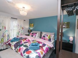 A bedroom with two beds with colorful bedding a window with floral curtains and a blue accent wall at 48 Aysgarth Rise in Bridlington
