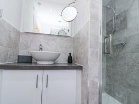 A bathroom with a sink on a countertop and a shower with grey tiles at 48 Aysgarth Rise Bridlington