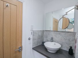 A bathroom sink with a round basin and faucet on a countertop with a mounted mirror and a wooden door at 48 Aysgarth Rise Bridlington