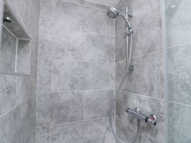 A shower area with gray tiles a handheld showerhead and a built in niche at 48 Aysgarth Rise Bridlington