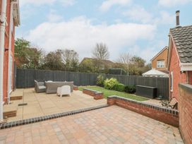 A backyard with patio furniture a paved patio and garden beds at 48 Aysgarth Rise Bridlington