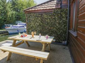An outdoor seating area with a picnic table and drinks near a boat at Heron Cottage