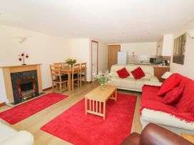 A living room with a fireplace and dining area at Heron Cottage