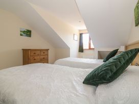 A bedroom with two beds and a dresser at Heron Cottage