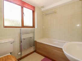 A bathroom with a bathtub, sink, and toilet at Heron Cottage