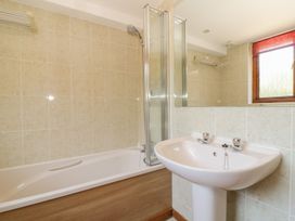 A bathroom featuring a bathtub, shower, sink, and window at Heron Cottage 