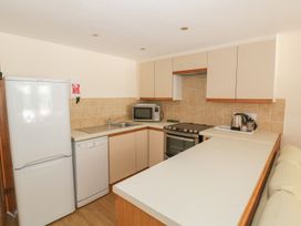 A kitchen with appliances including a refrigerator and oven at Heron Cottage