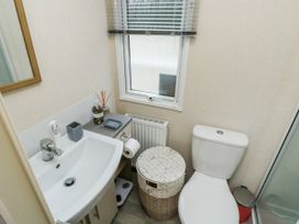 A bathroom with a sink toilet wicker laundry basket window and small trash bin at Ocean Pearl in Kingsbridge
