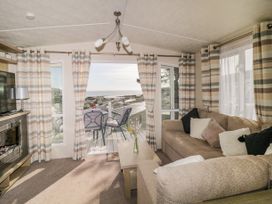 A living room with a sofa a coffee table a television and a glass door leading to a balcony at Ocean Pearl in Kingsbridge