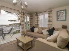 A living room with a beige sofa and cushions a wooden coffee table and striped curtains at Ocean Pearl in Kingsbridge