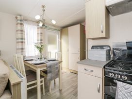 A kitchen dining area with a table set for four chairs a stove and cabinets at Ocean Pearl in Kingsbridge