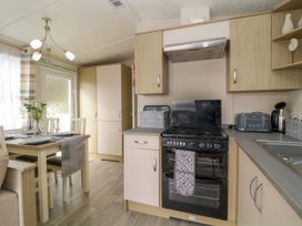 A kitchen with a dining table set for four with flowers on it and appliances including stove toaster and kettle at Ocean Pearl in Kingsbridge
