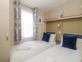 A bedroom with two single beds with blue pillows and white bedding at Ocean Pearl in Kingsbridge